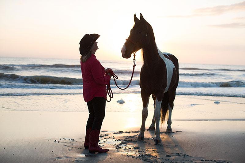 黛比和她的马在日落海滩上骑马
