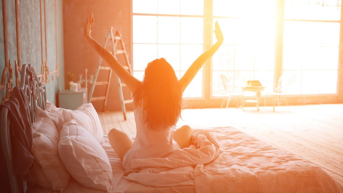 woman stretching out of bed at dawn